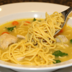 Soulful chicken soup with egg noodles, tender chicken pieces, and vegetables in a golden broth.