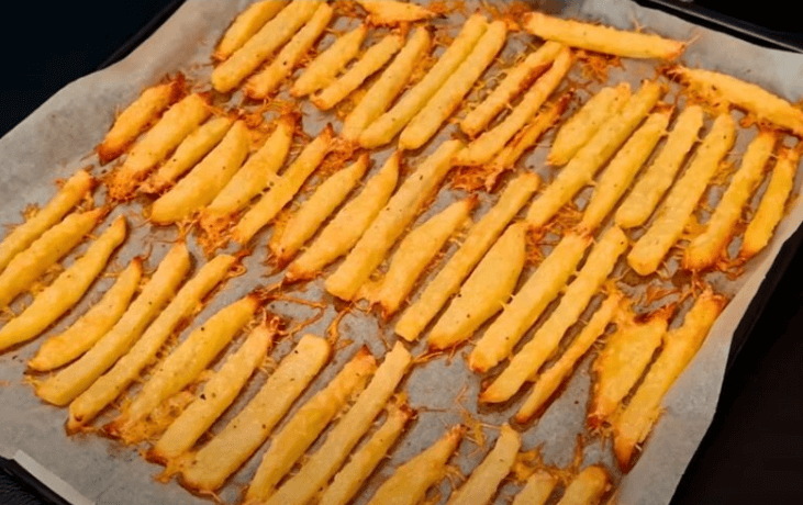 Crispy baked Parmesan potato fries on a parchment-lined baking tray